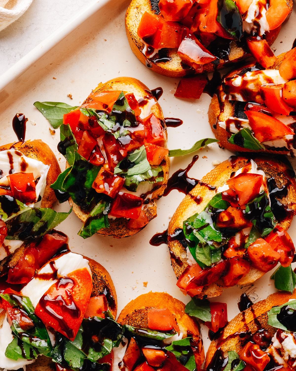 Overhead tray of bruschetta with mozzarella, tomato and basil.