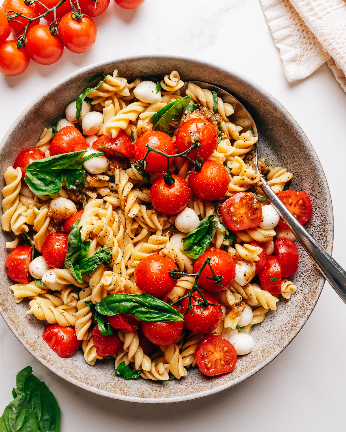 Caprese pasta salad in a bowl with cherry tomatoes, fresh mozzarella, and basil.