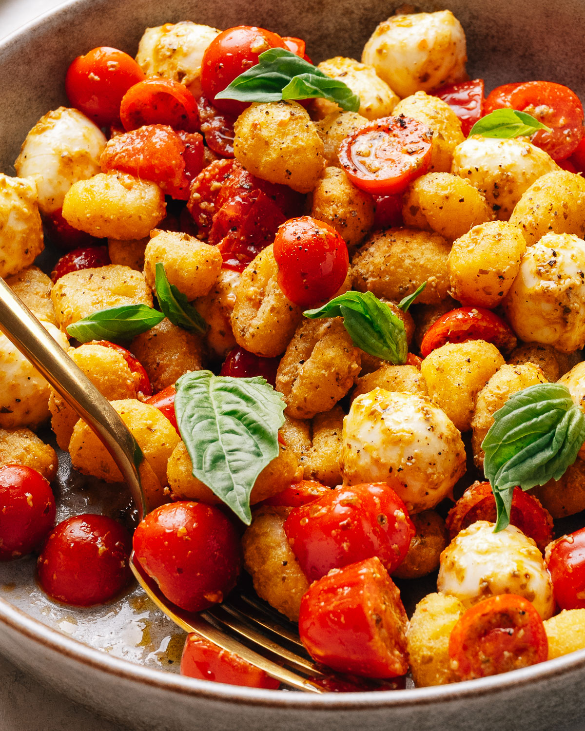 A plated portion of gnocchi salad with golden crisp gnocchi and fresh basil.