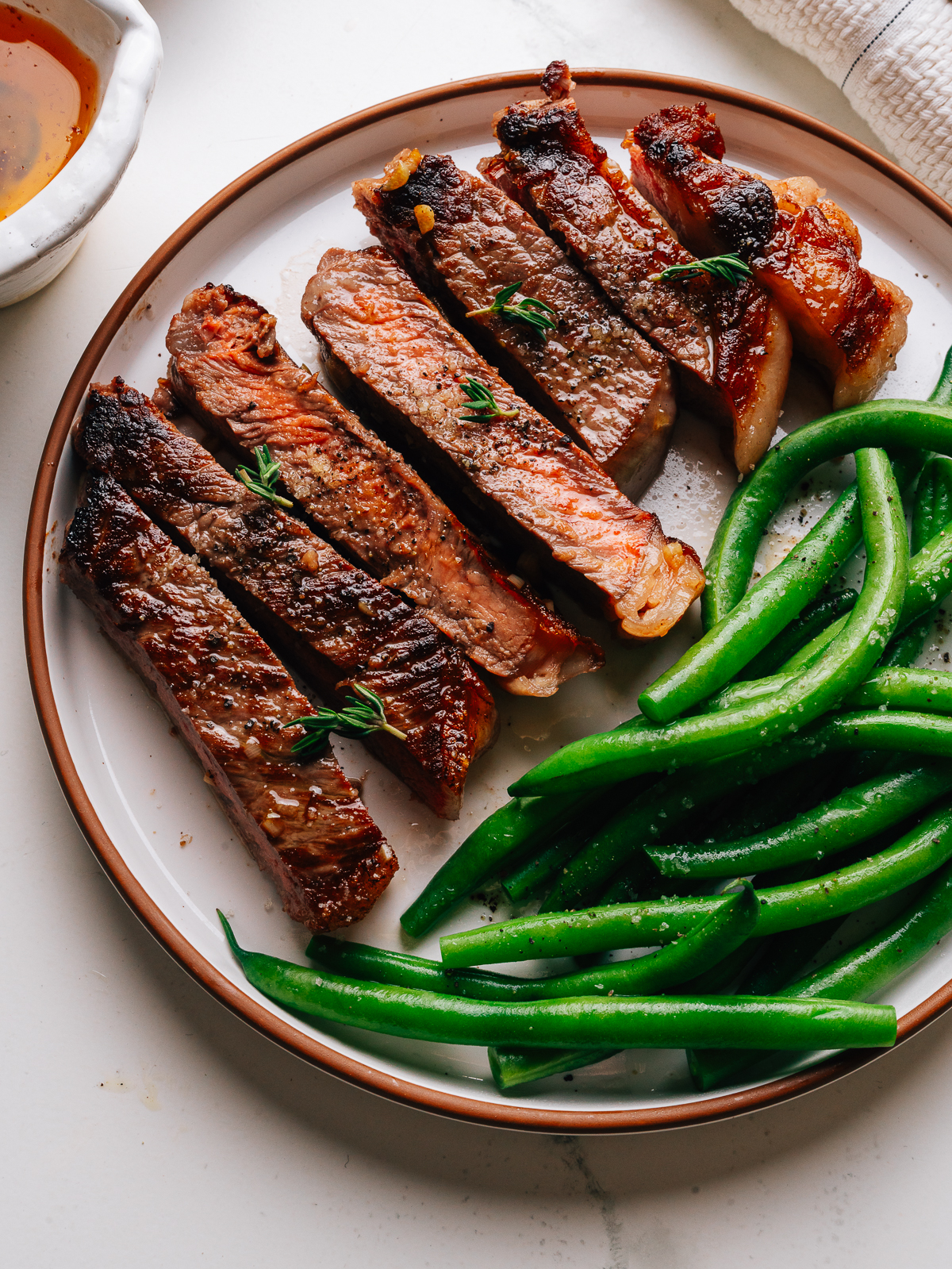 Overhead of sliced garlic butter steak with green beans on a plate.