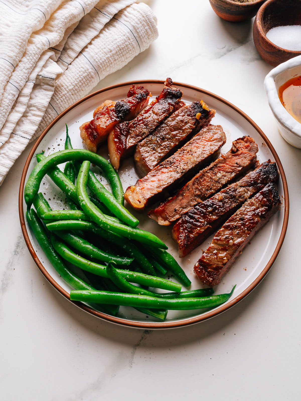 Garlic butter steak sliced and plated with green beans and pan butter.