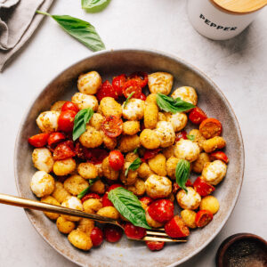 Crispy gnocchi salad with pesto, cherry tomatoes and bocconcini in a serving bowl.