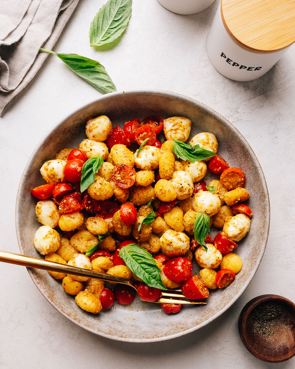 Crispy gnocchi salad with pesto, cherry tomatoes and bocconcini in a serving bowl.