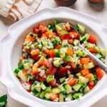 Israeli salad with diced cucumber, tomato, and red onion in a white bowl.