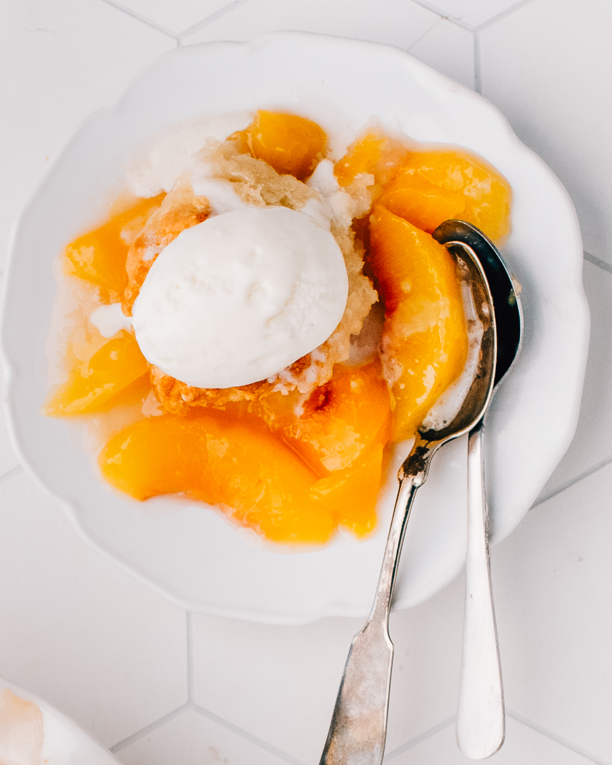 Overhead bowl of peach cobbler with a scoop of vanilla ice cream.