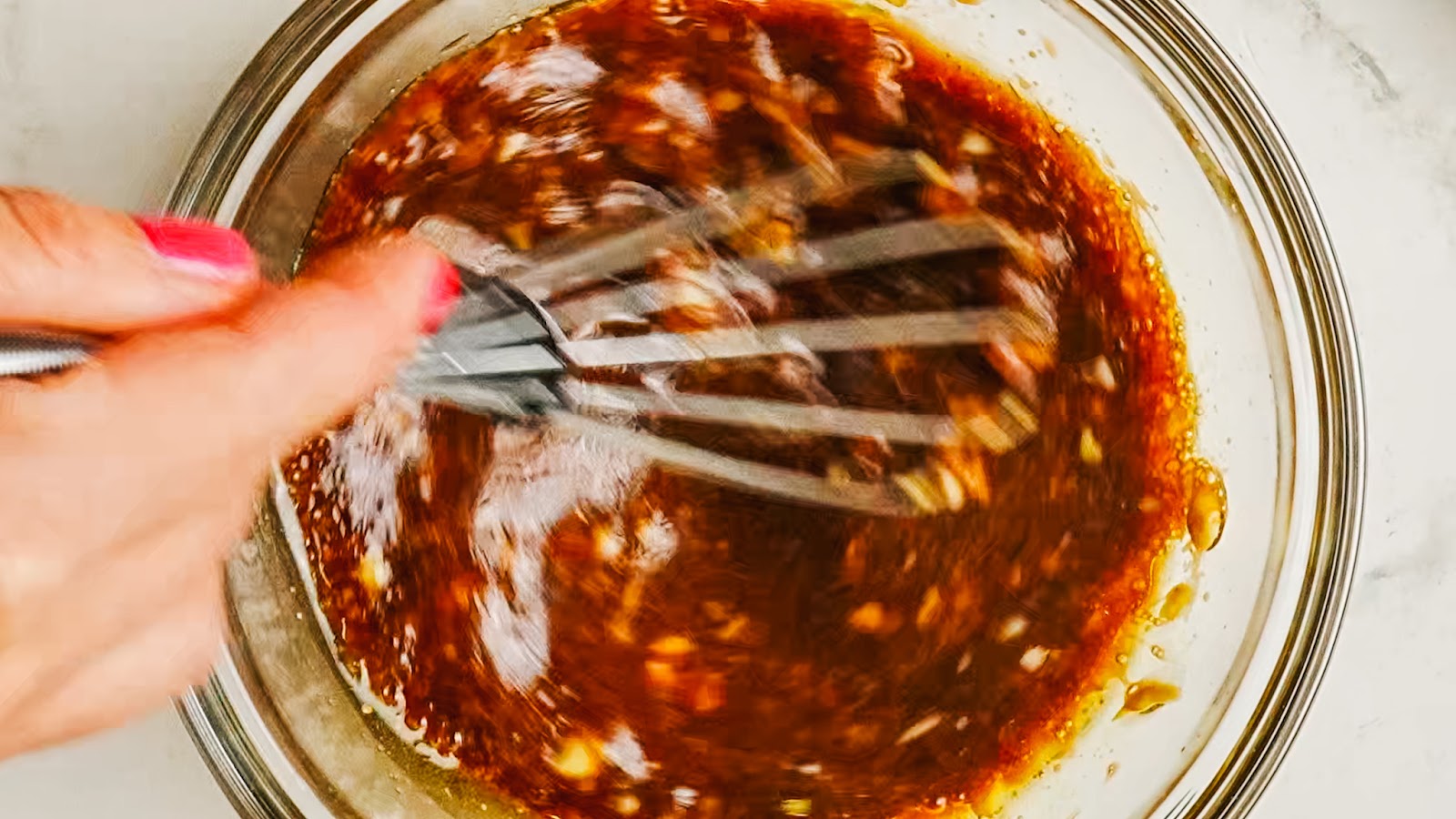 Whisking the dark balsamic marinade in a bowl.