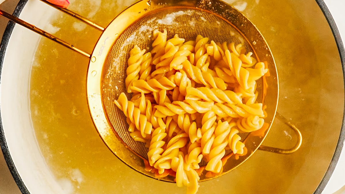Cooked pasta lifted from the pot for caprese pasta salad.