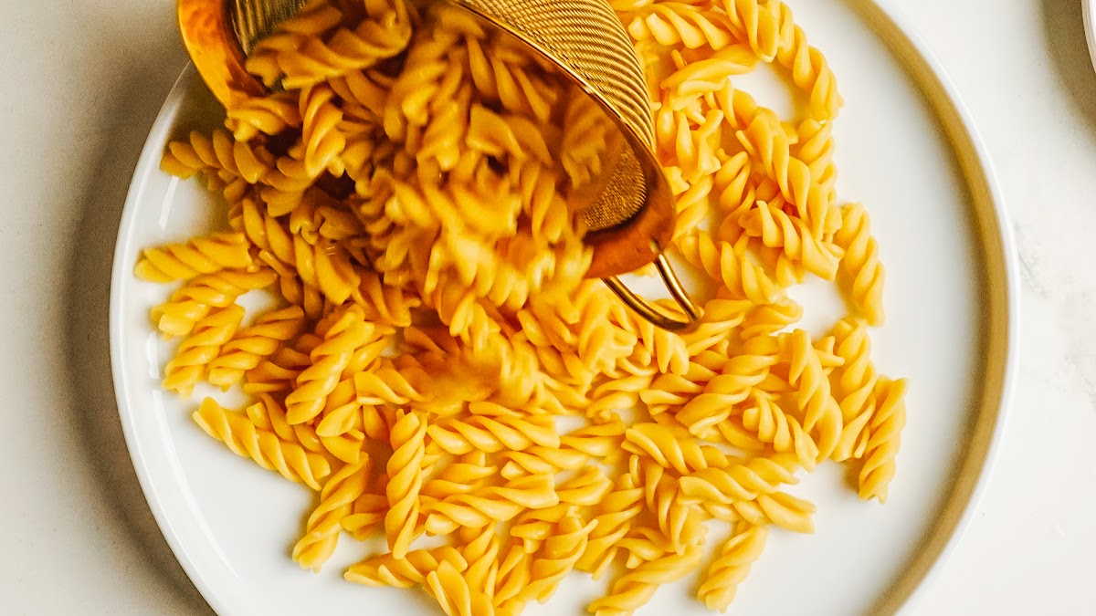 Cooked pasta spread out to cool for caprese pasta salad.