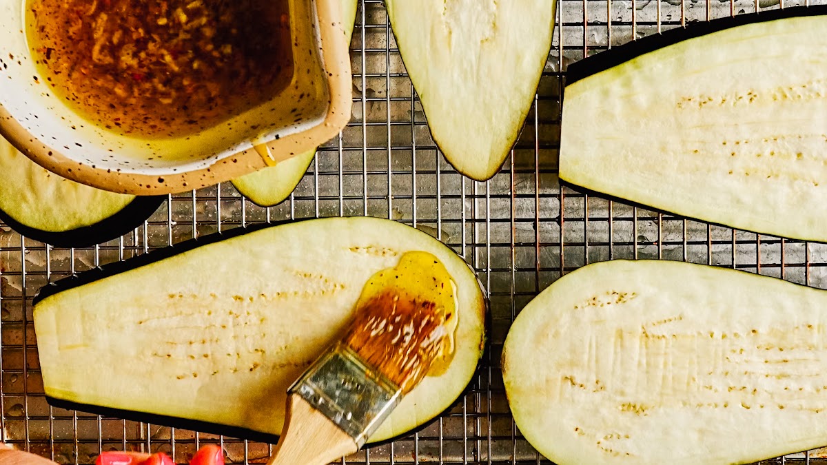 Brushing garlic oil over eggplant slices on a rack.