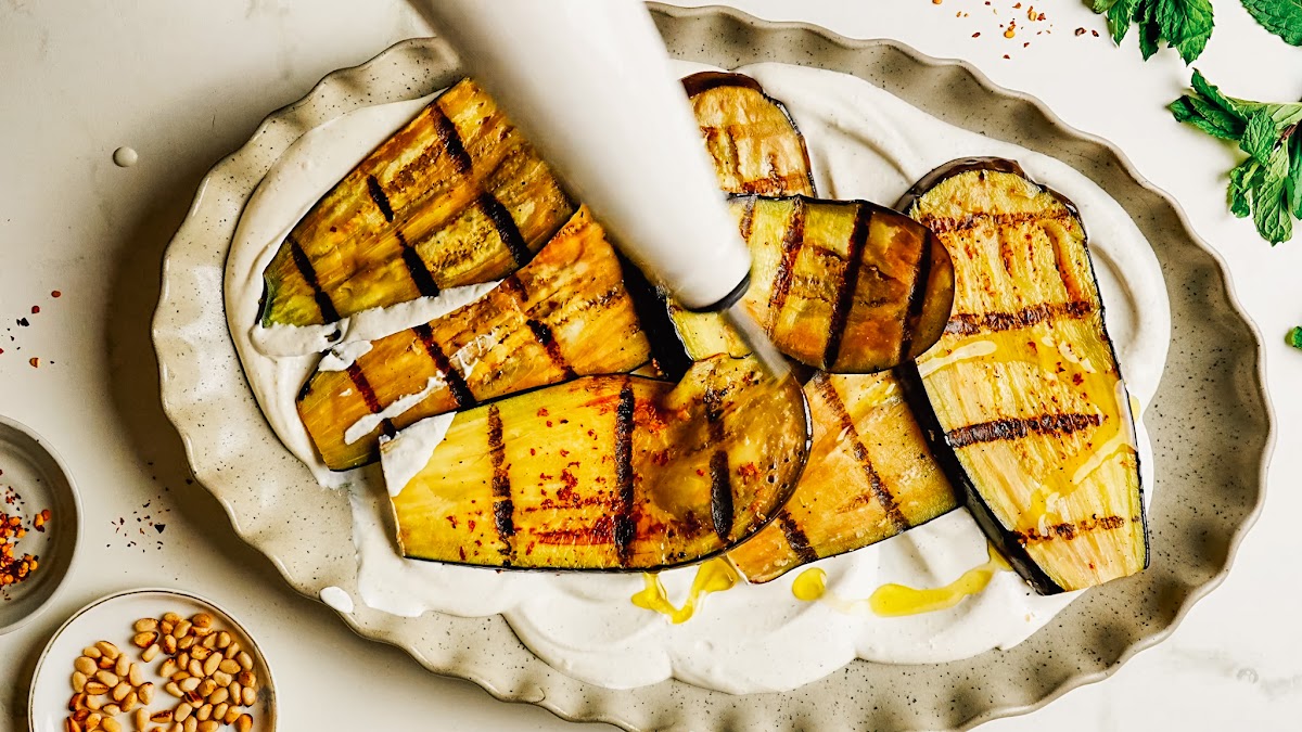 Close view of charred grilled eggplant over creamy whipped feta.