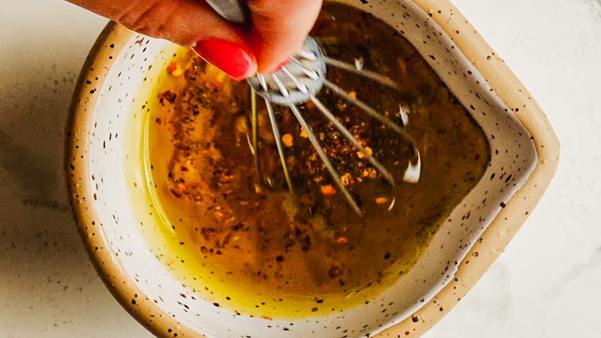 Whisking garlic oil marinade in a small bowl.