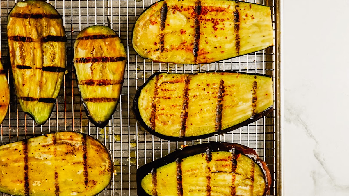Grilled eggplant slices with char marks on the grill.