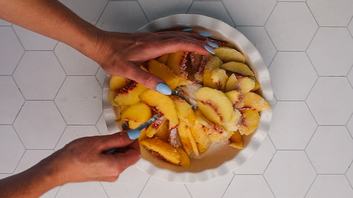 Tossing peaches with sugar and cinnamon for peach cobbler filling.