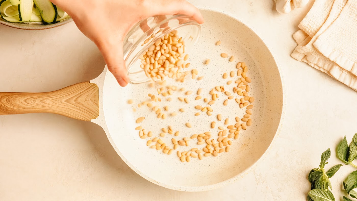 Toasting pine nuts in a dry skillet until golden.