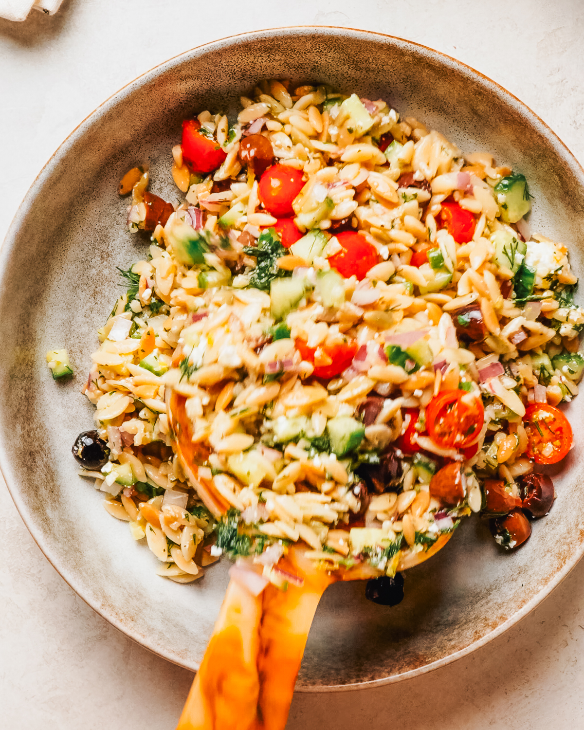 Orzo pasta salad with cucumber, cherry tomatoes, olives and feta in a bowl.