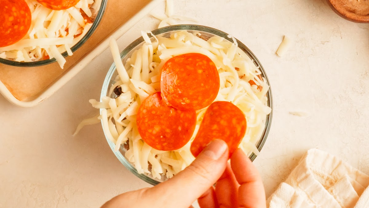Step 3: pepperoni layered over shredded mozzarella in a glass pizza bowl.