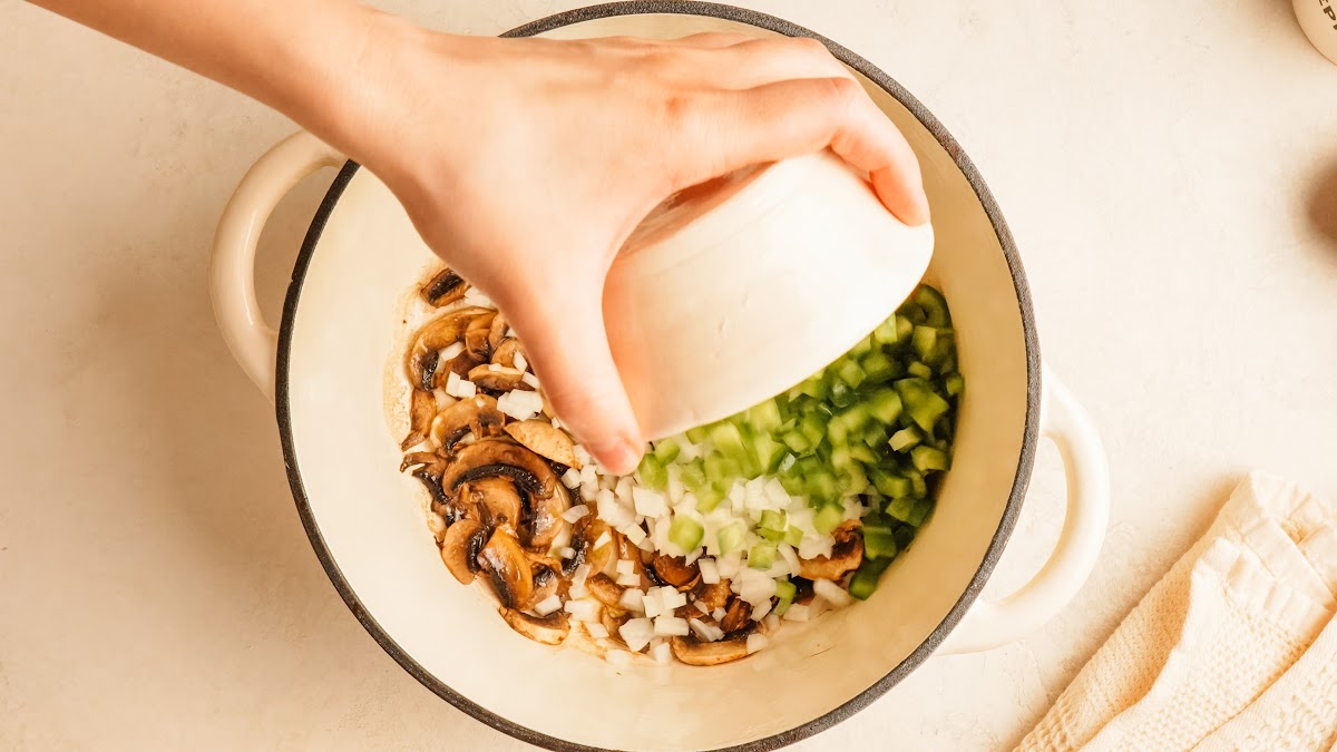Step 2: mushrooms, onion, and green pepper cooking together in a pot.
